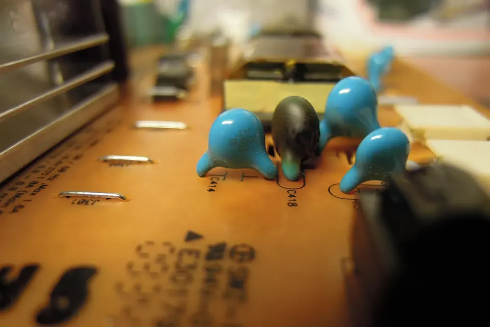 Close-up of a burnt high-voltage capacitor on the adapter and inverter board of an LCD TV, with scorch marks on the board around it
