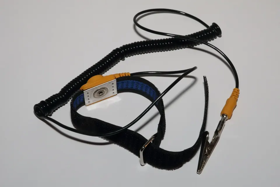 An antistatic wrist strap with its coiled earth lead and crocodile clip on a white surface